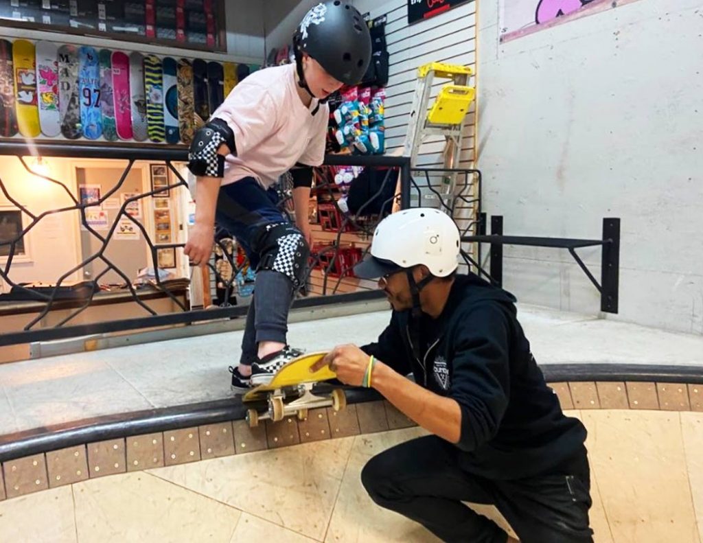 Homem ensinando menino a subir no skate