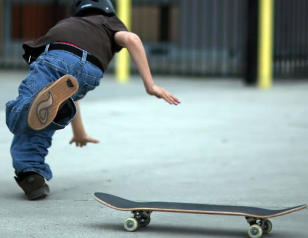 Menino iniciante no skate tendo sua primeira queda