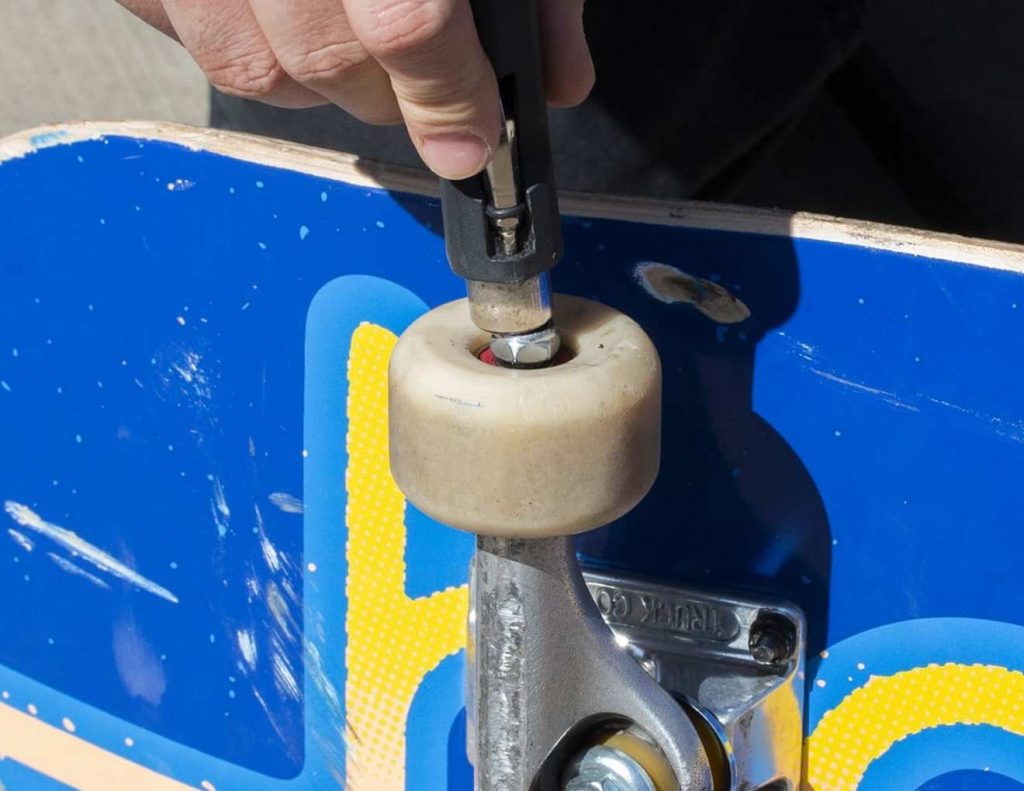 Rodas de skate sendo instaladas no truck durante a montagem